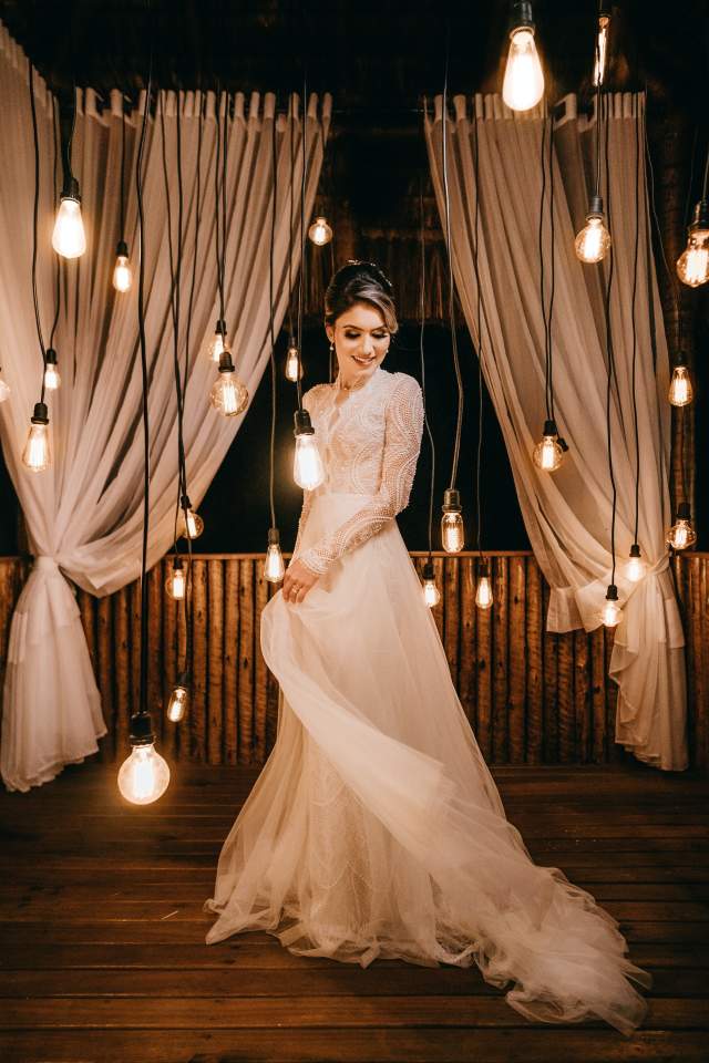 Bride in wedding gown among hanging lights