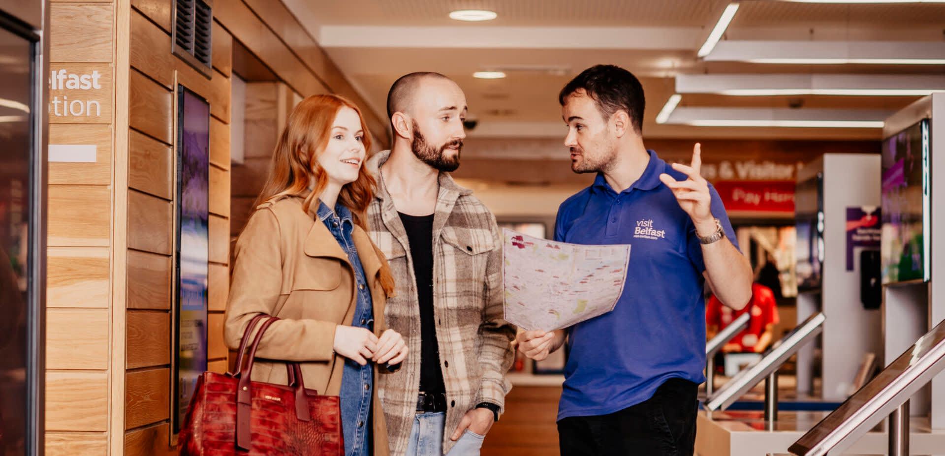 Staff helping a couple in the Visit Belfast Welcome Centre.