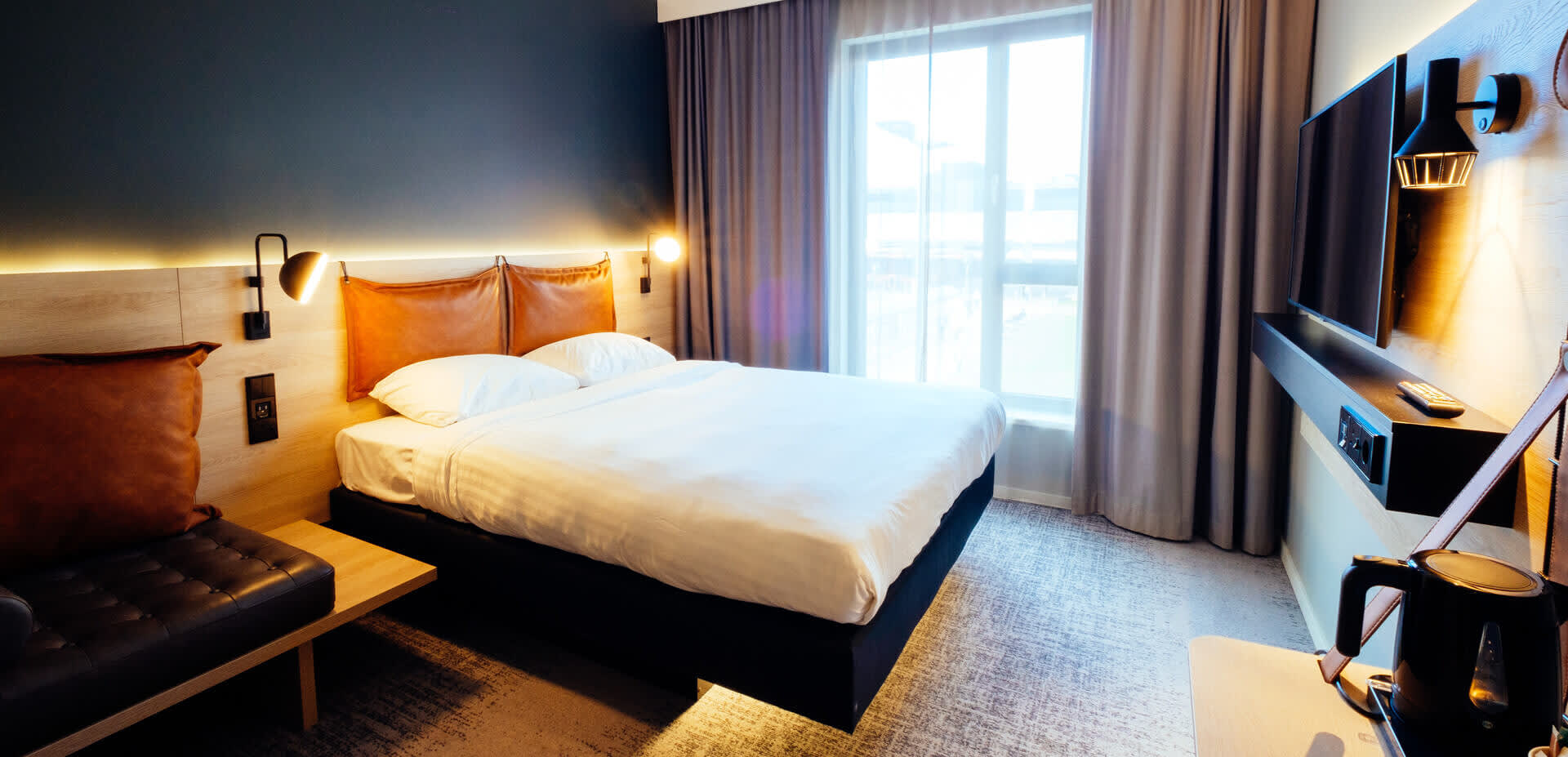 A pristine room in a hotel, a floating bed in the centre, from under which light spills out.