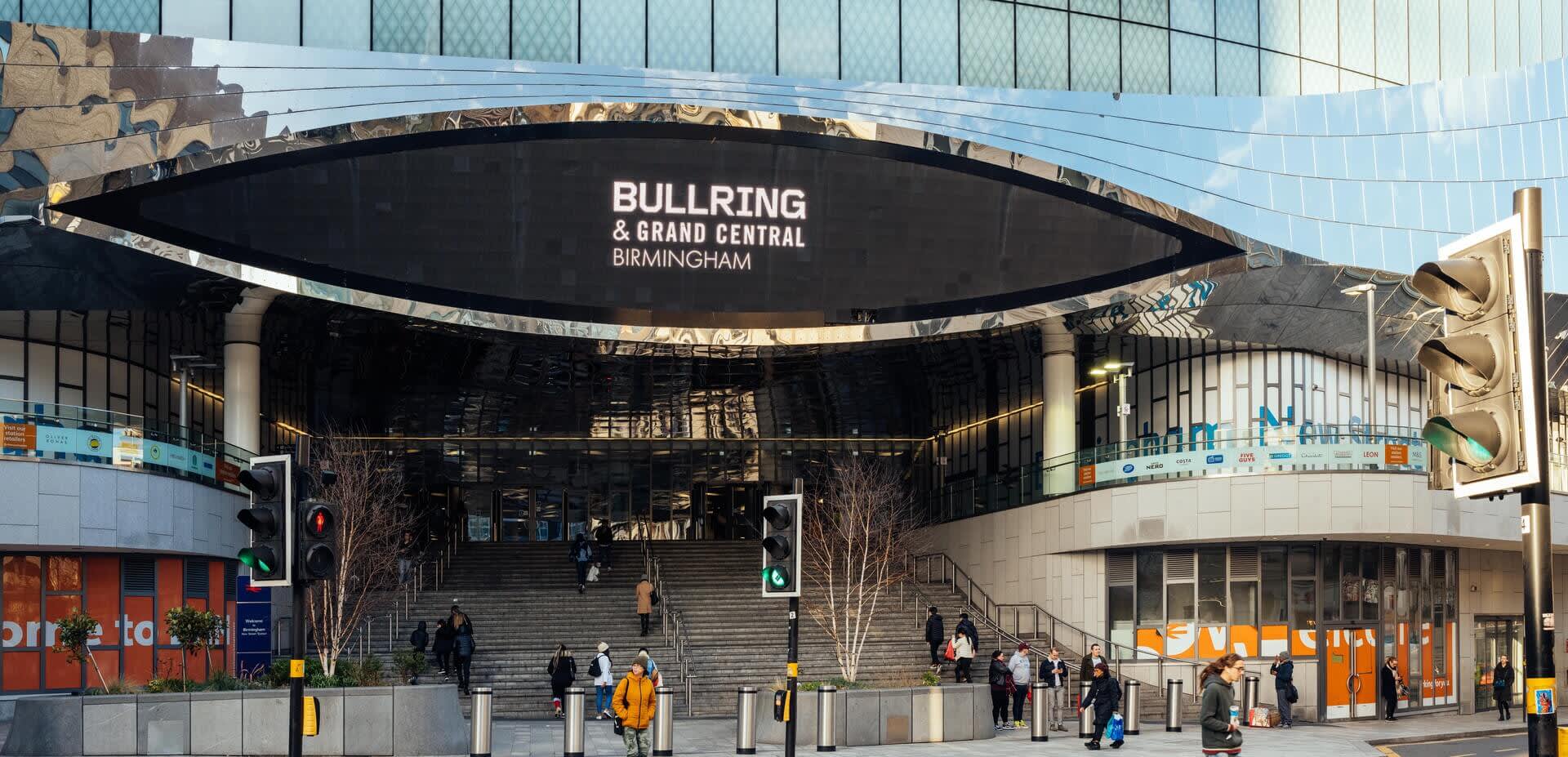 A large oval sign reads 'Bullring and Grand Central Birmingham' on the front of a mirrored building above the main entrance.
