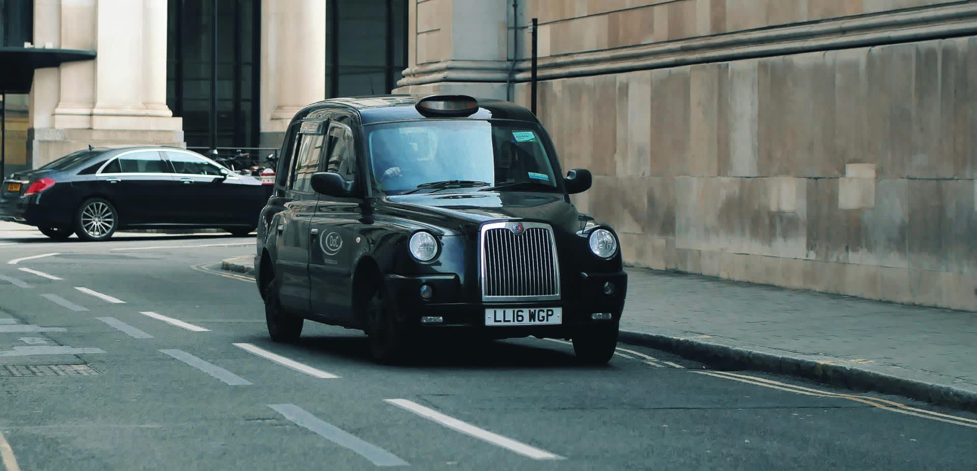 A taxi waiting at the side of the road for a passenger