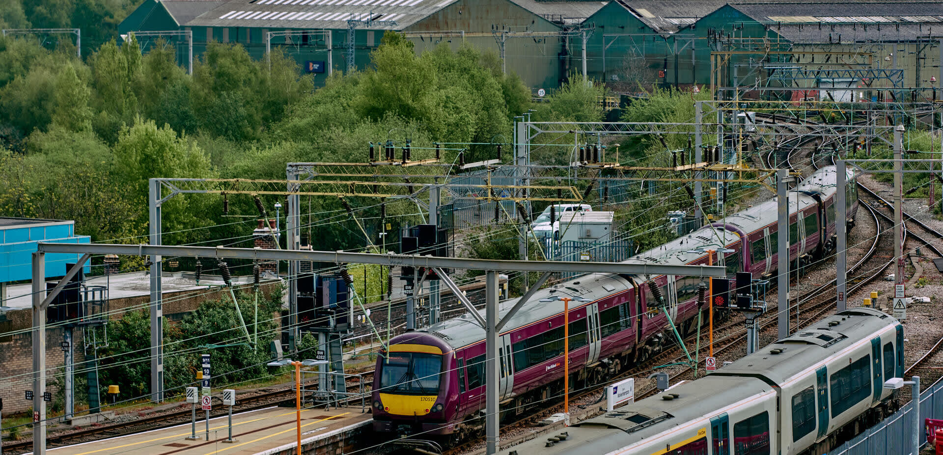 Wide view photograph of train tracks coming into the city, with a West Midlands Railway train on the tracks
