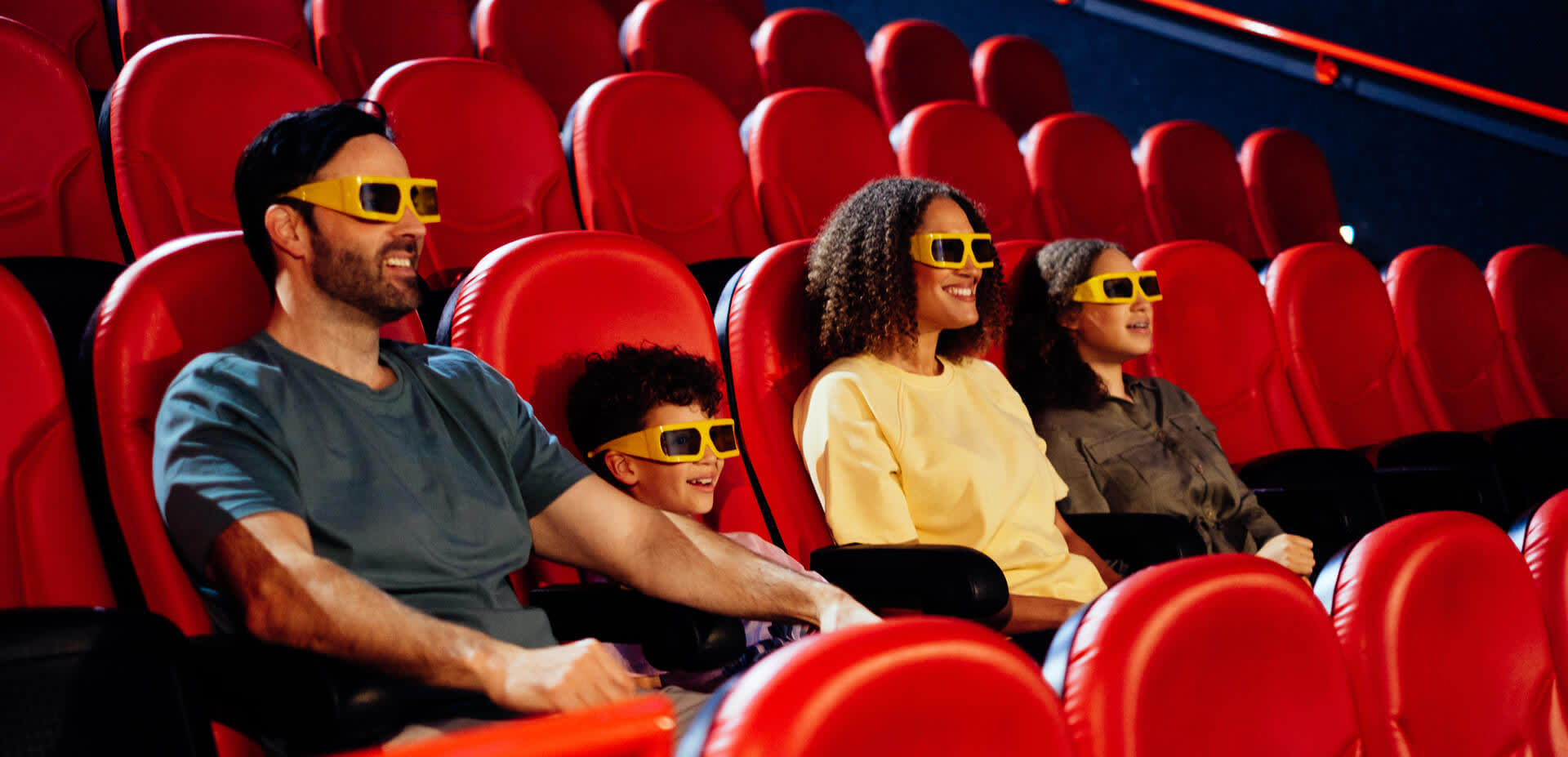 A family of four - Dad, son, mom, daughter sat in a cinema with 4D glasses on