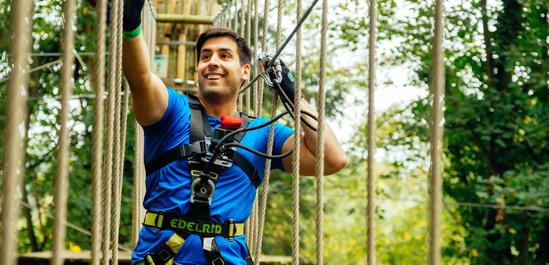 A man crosses a rope bridge high in the trees at Bear Grylls Adventure