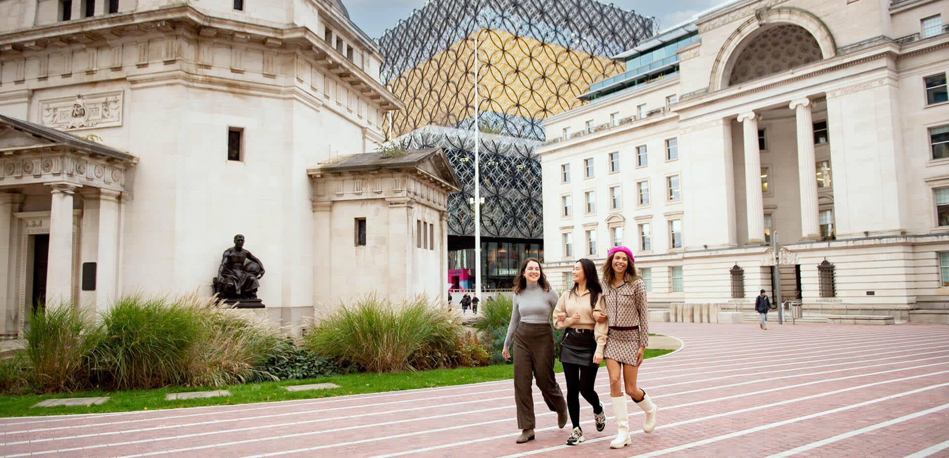 Three ladies walking at the back of Centenary Square with the Library of Birmingham in the background.