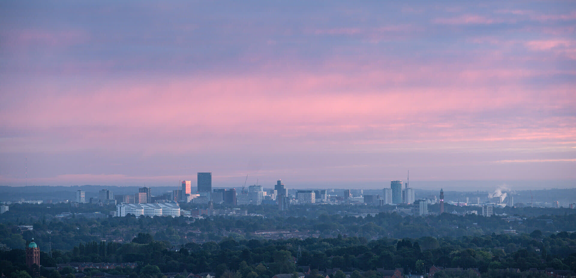 The Birmingham skyline in the far distance below a purple evening sky