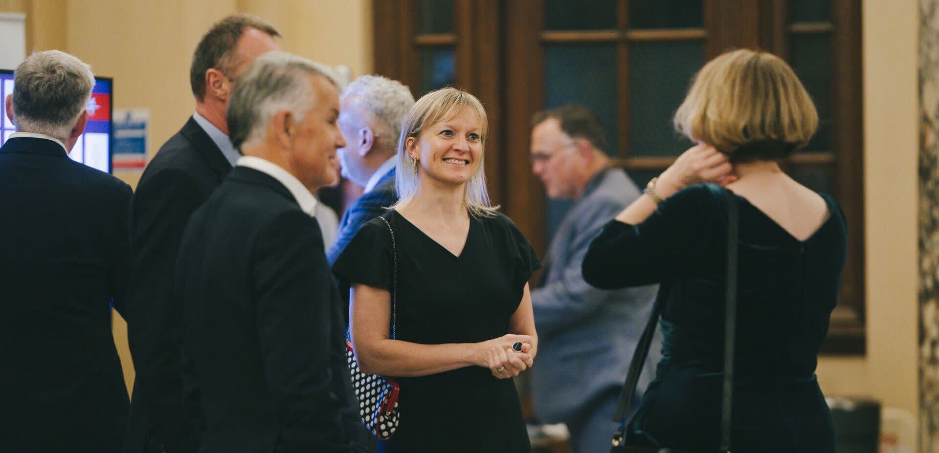 Partners and stakeholders talk at a black tie investment event.