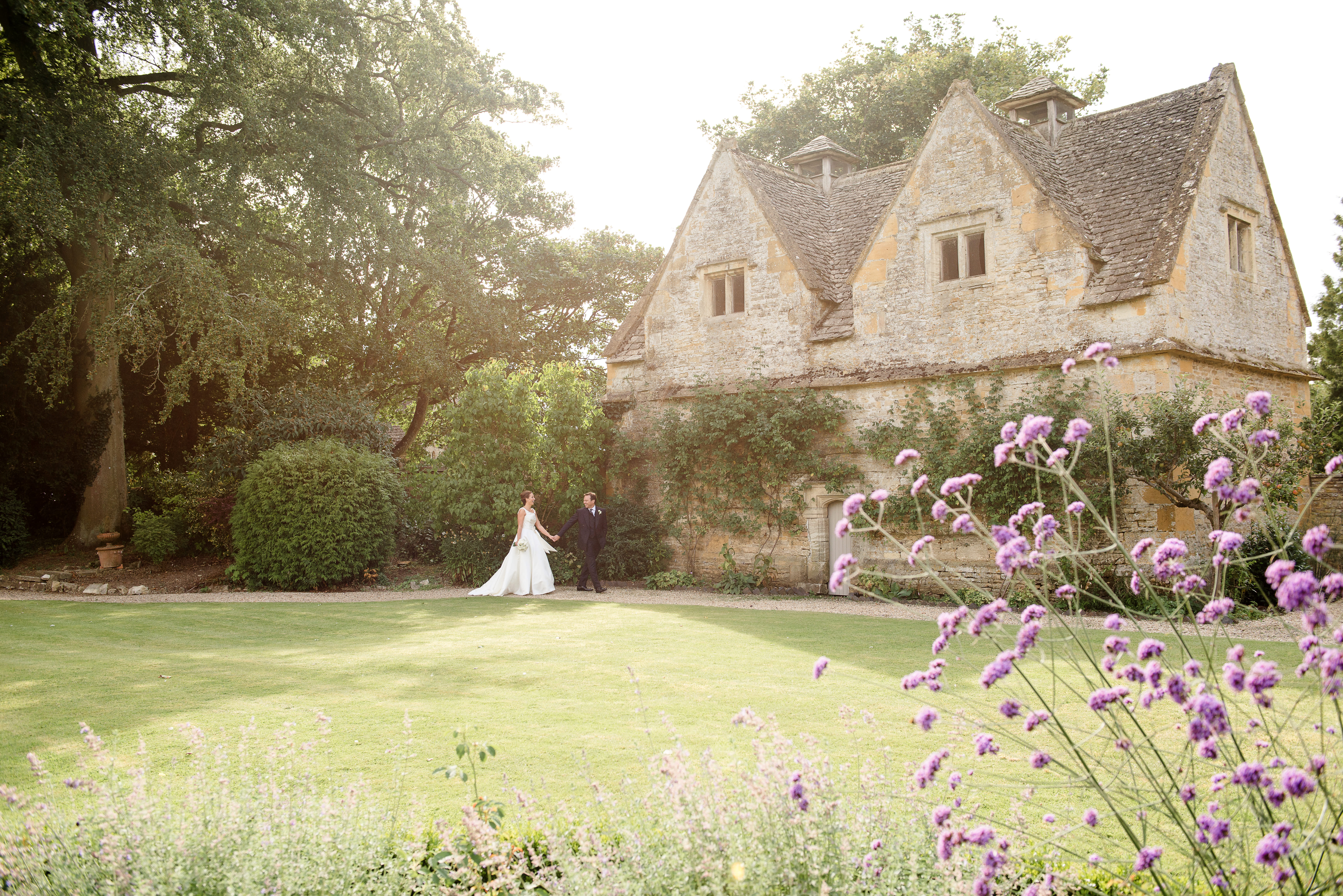 A bride and groom walk through the stunning grounds of The Slaughters Manor House