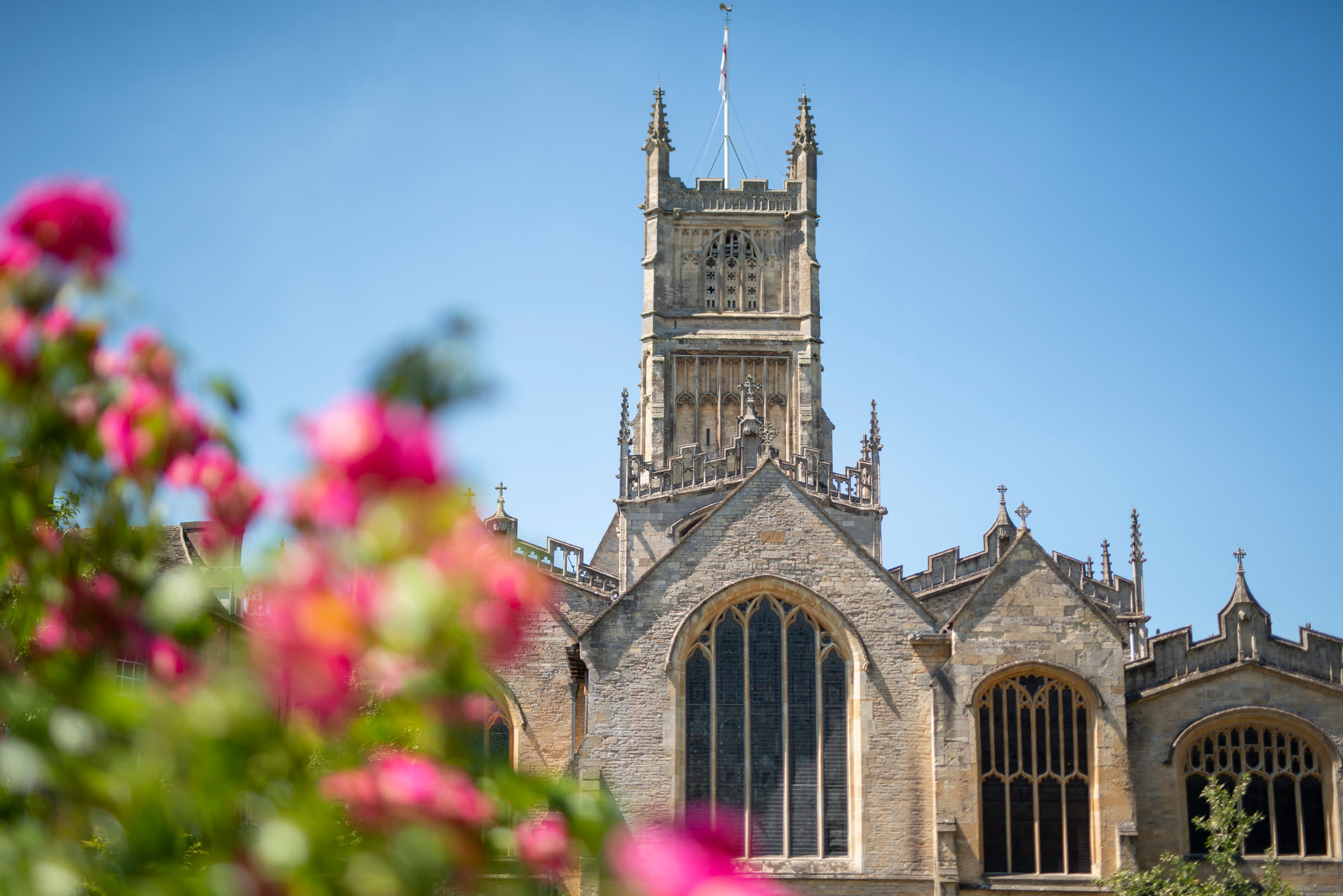 Cirencester in the summer, The church against a blue sky and pink flowers