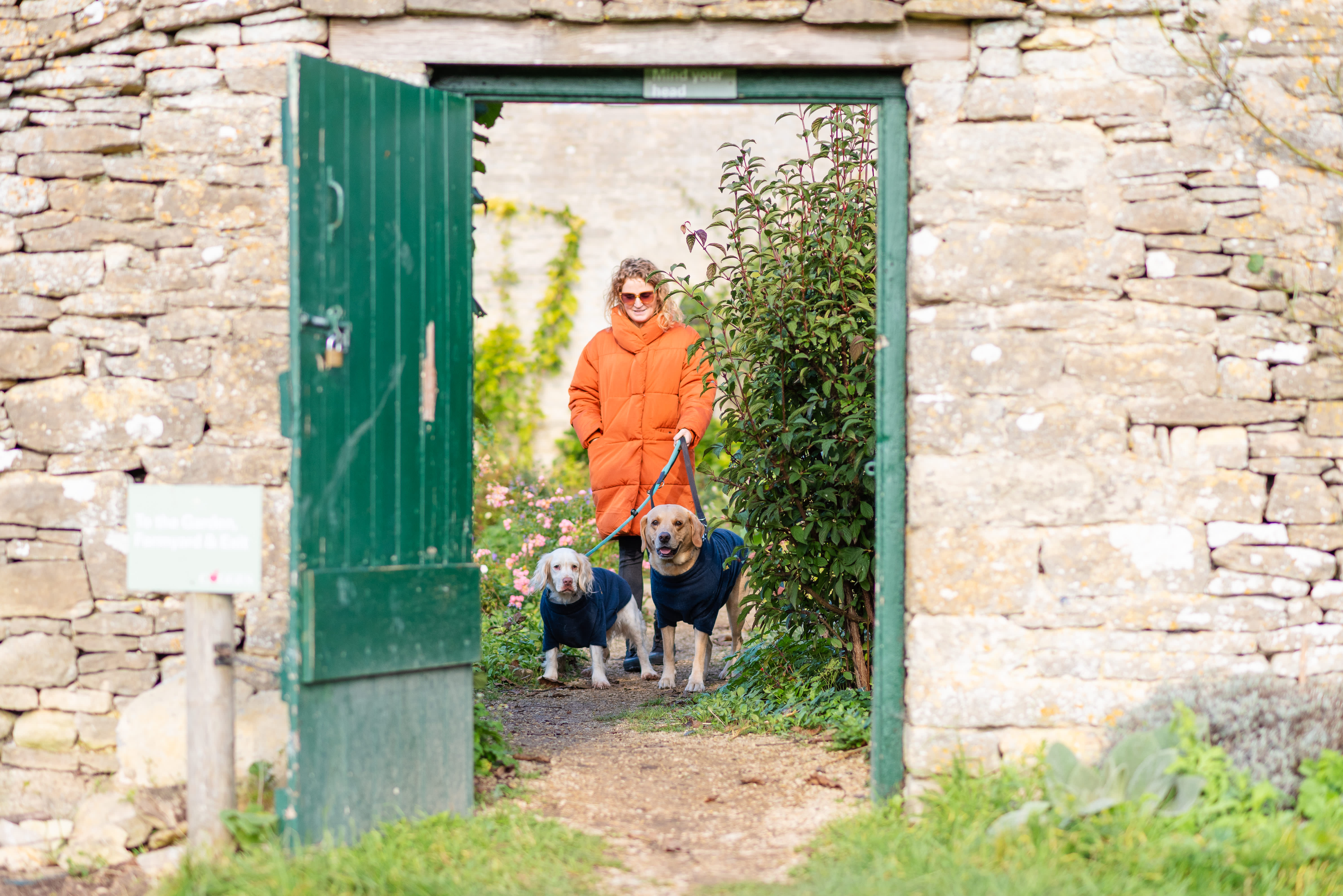 Woman and dogs walking out of the kitchen garden at Cogges Manor Farm
