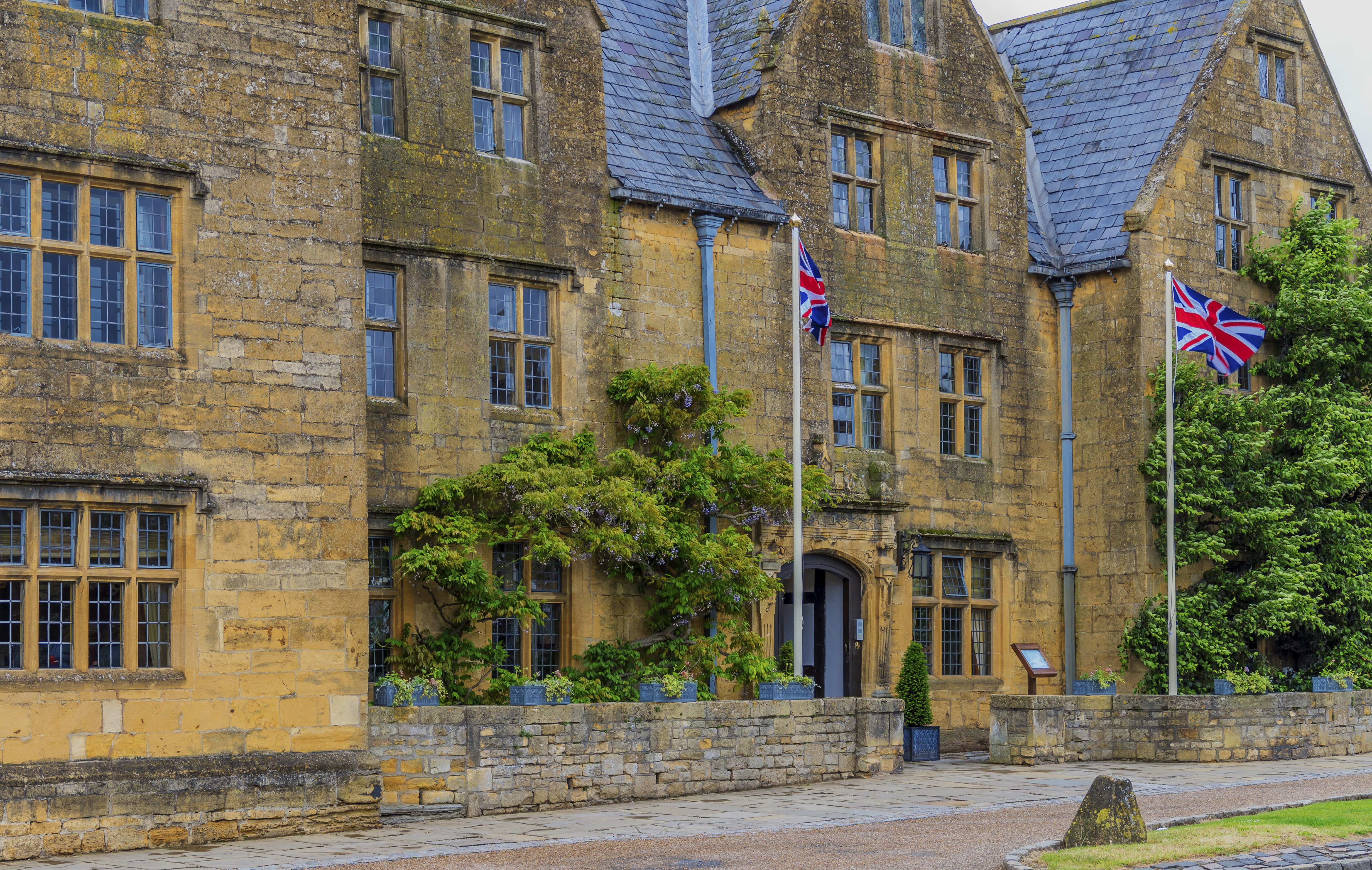 The honey-coloured Lygon Arms, in the Cotswolds, draped in wisteria with Union Jack flags flying