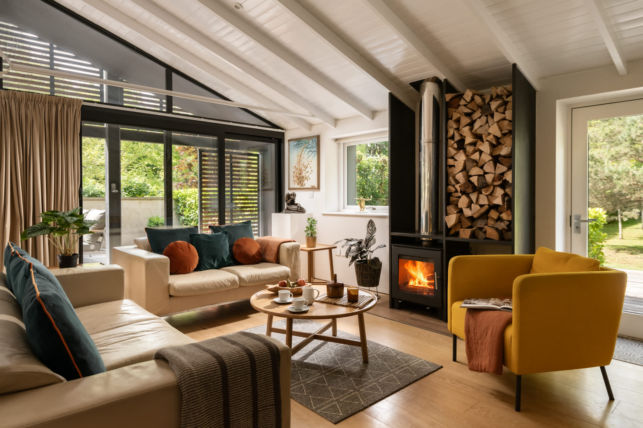 A modern lakeside property with the fire roaring facing the 2 sofas and armchair. Be.Here. in the Cotswolds