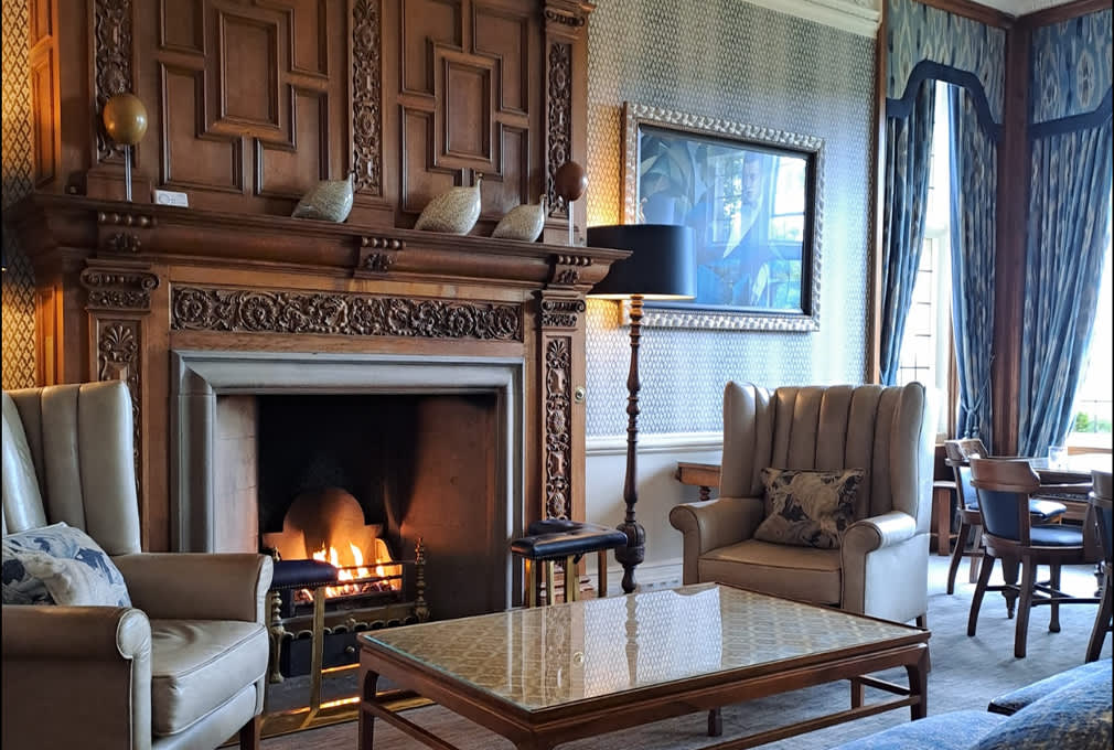 a lounge with open fire armchairs and sofa in Bovey Castle