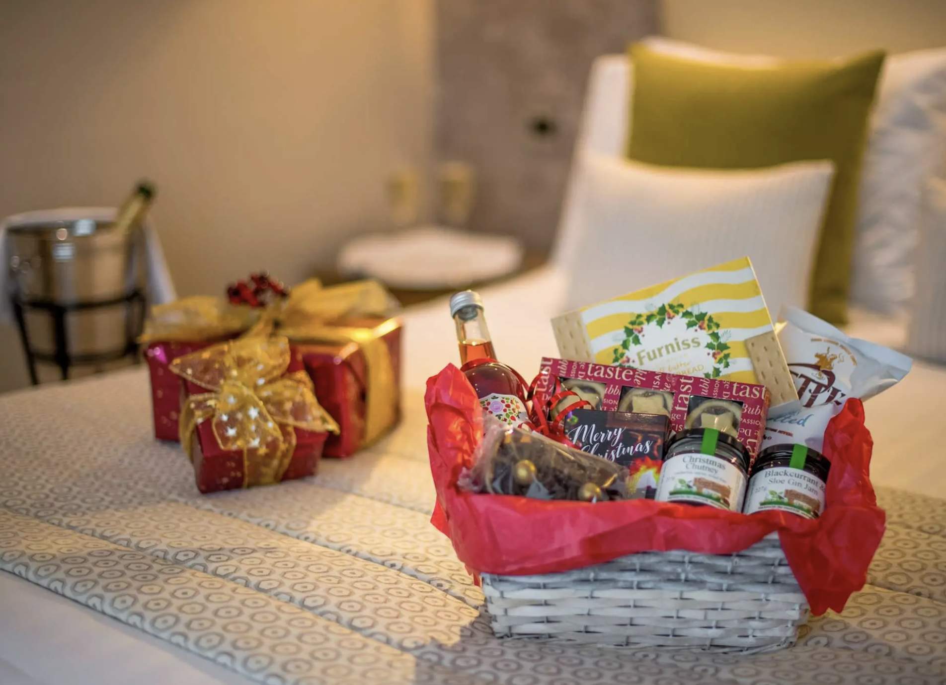welcome basket with goodies on a bed in a hotel christmas presents in a background