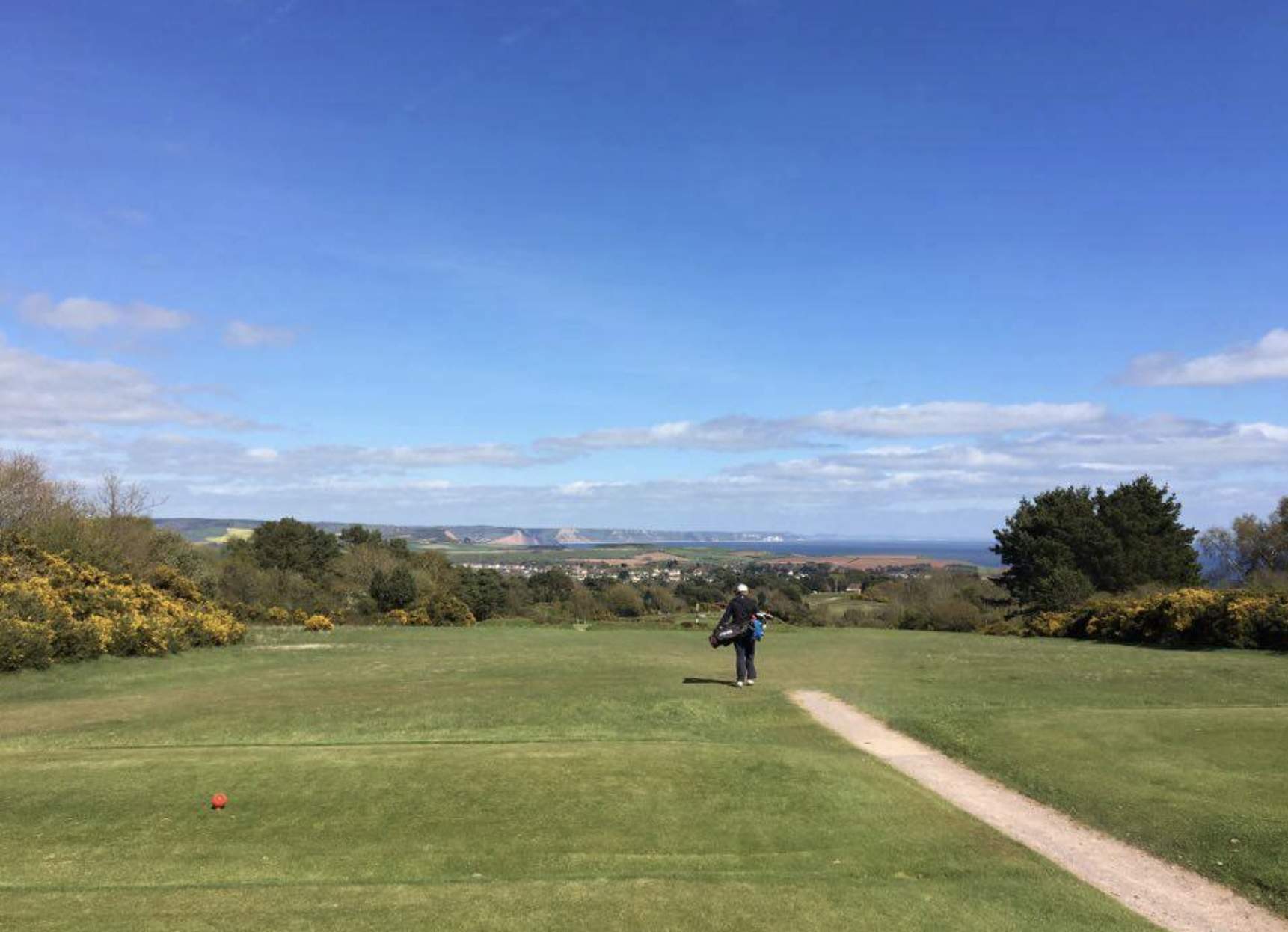 golf course and a golfer walking away sea view landscape in a disctance