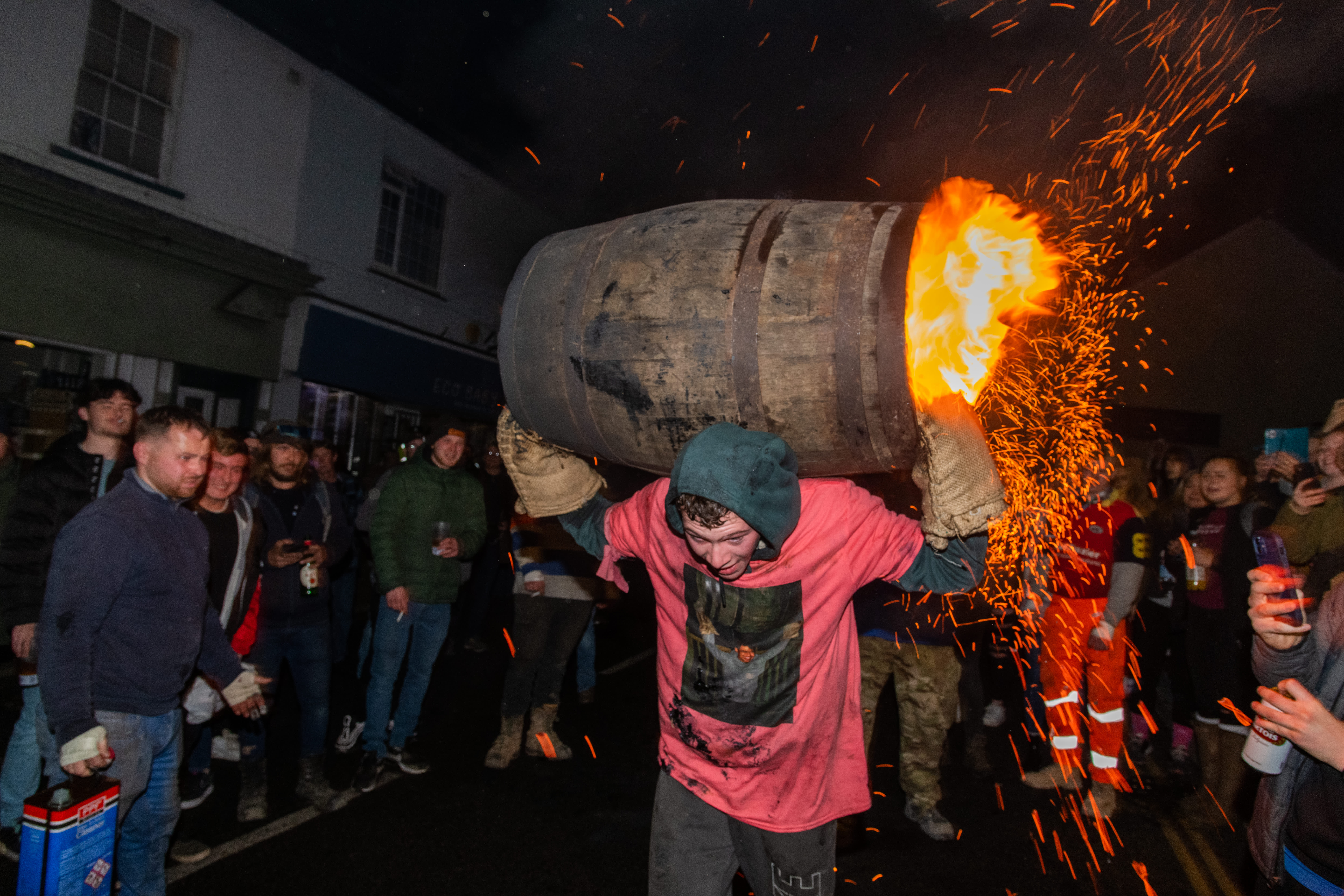 man carrying a barrel which is on fire
