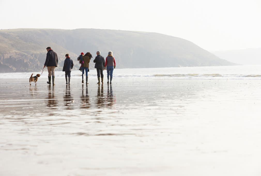 family woalking a dog on a beach in winter