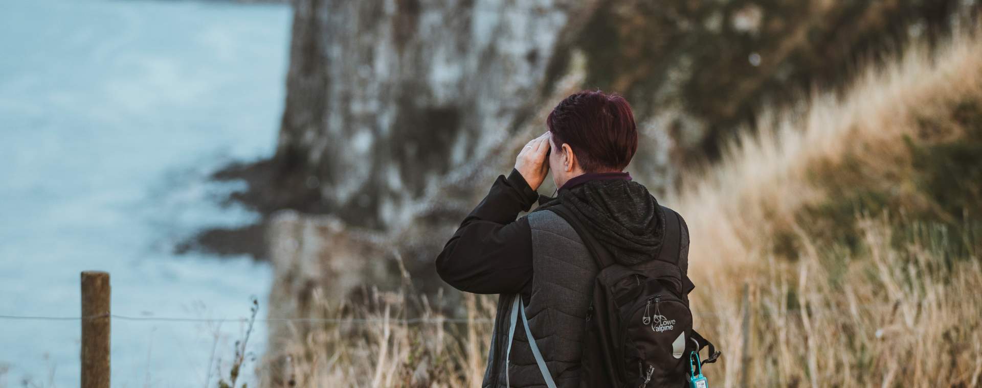 A person looking through binoculars out to sea at Bempton Cliffs