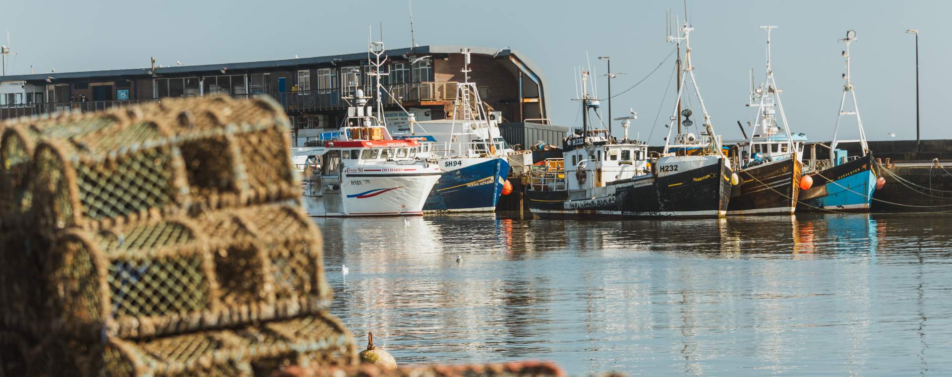 Lobster pots stacked on Bridlington harbour with boats in the background