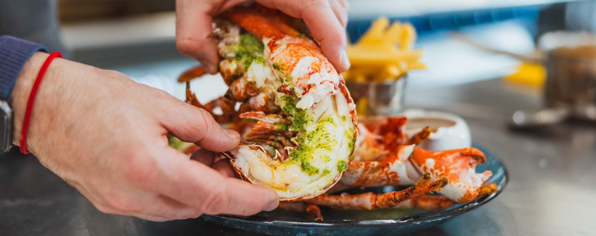 A close up of hands arranging freshly cooked lobster on a plate