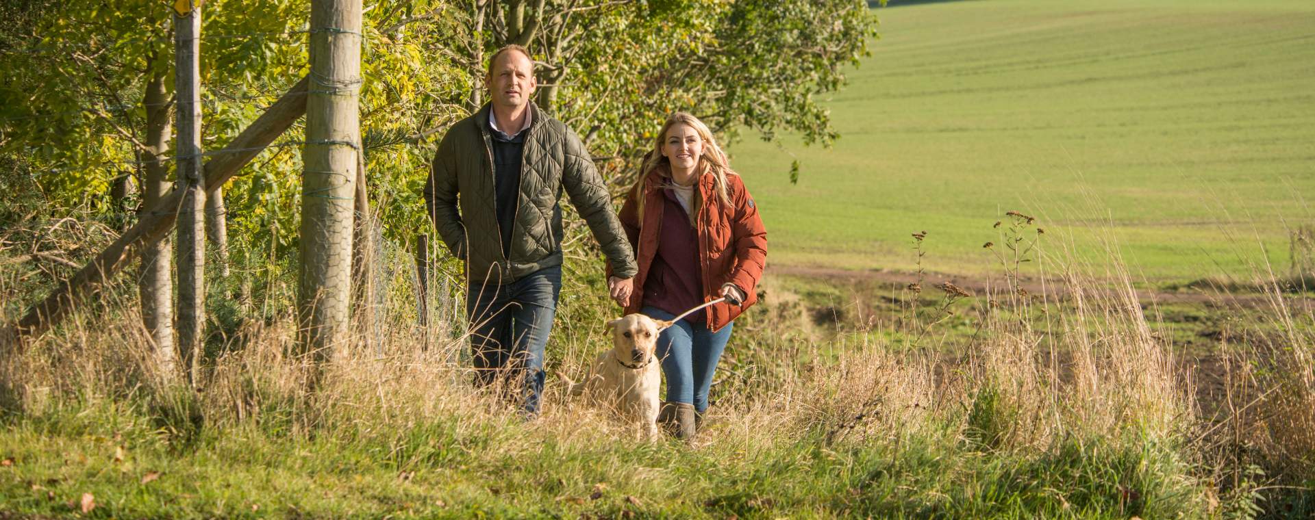A couple walking across the Yorkshire Wolds with a dog