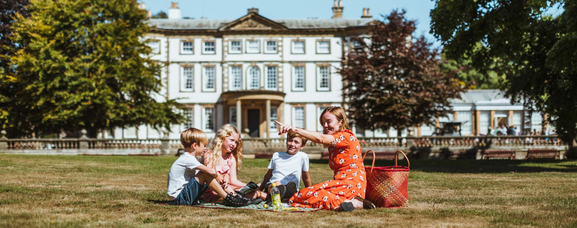 Family sat on the grass with Sewerby Hall in the background