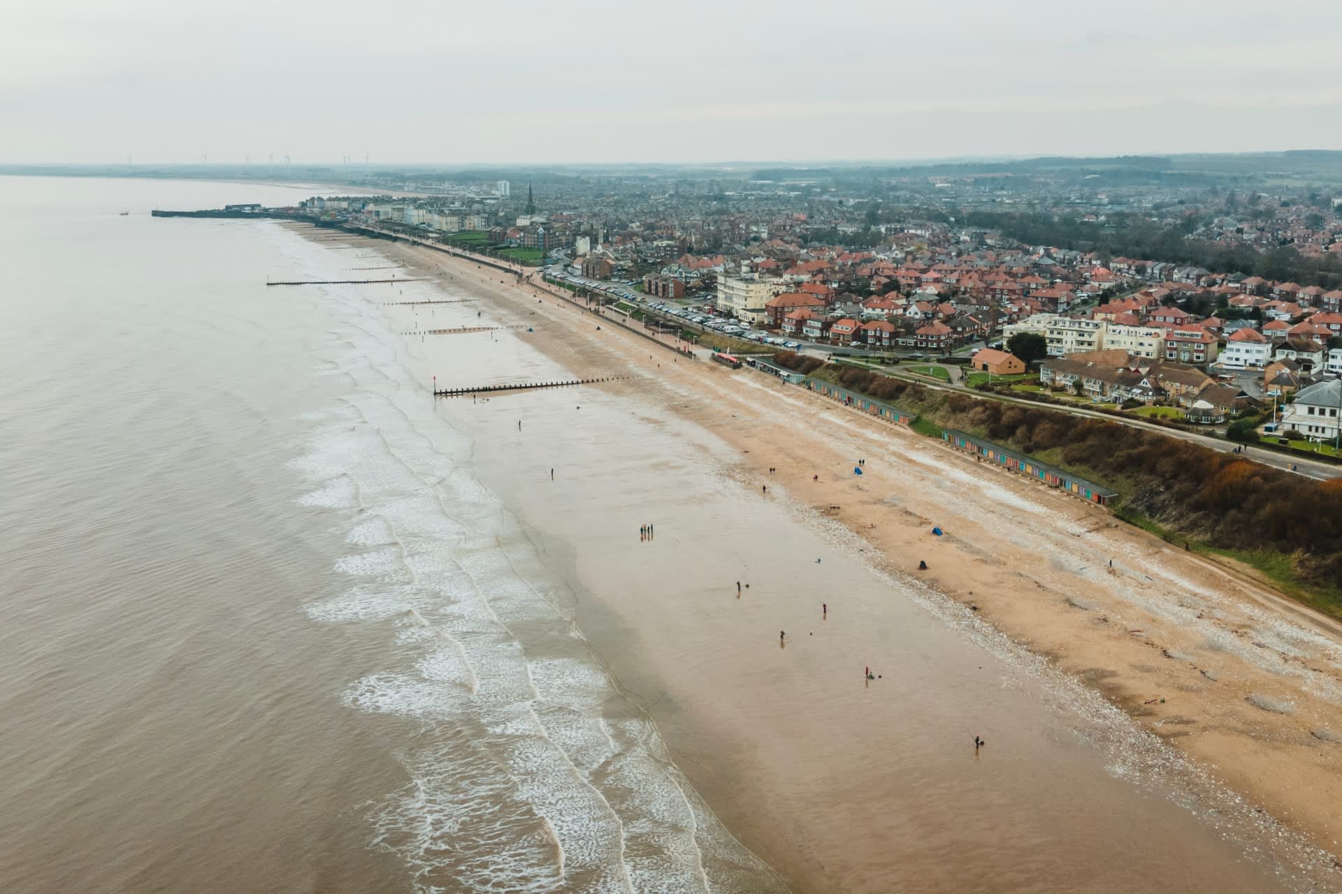 aerial shot of anglers along the coastline with the town in the background