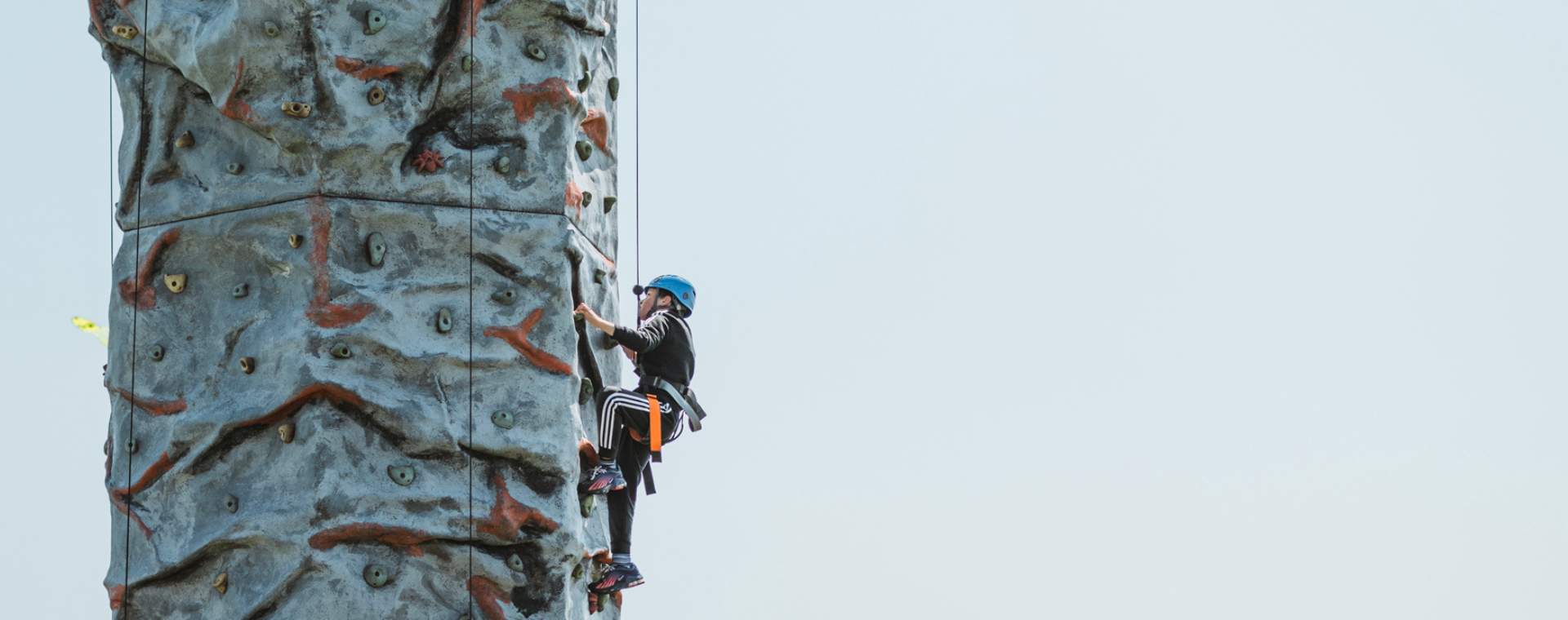 Little boy scaling an outdoor climbing wall at an event in East Yorkshire