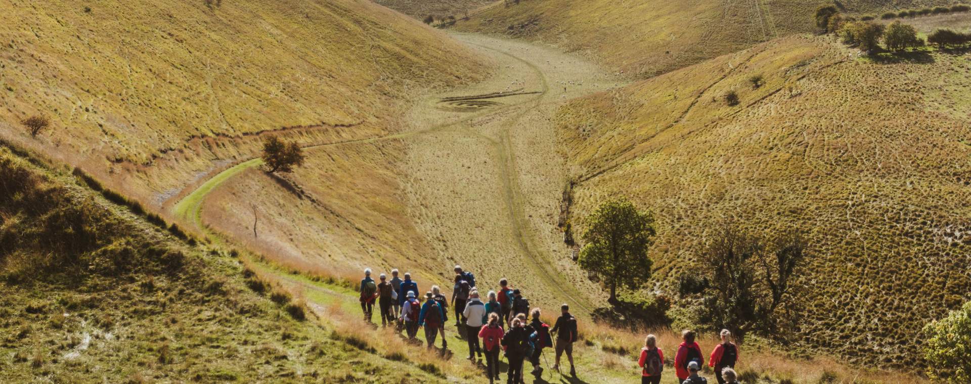 A vast valley in the Yorkshire Wolds with a group of walkers heading towards the bottom