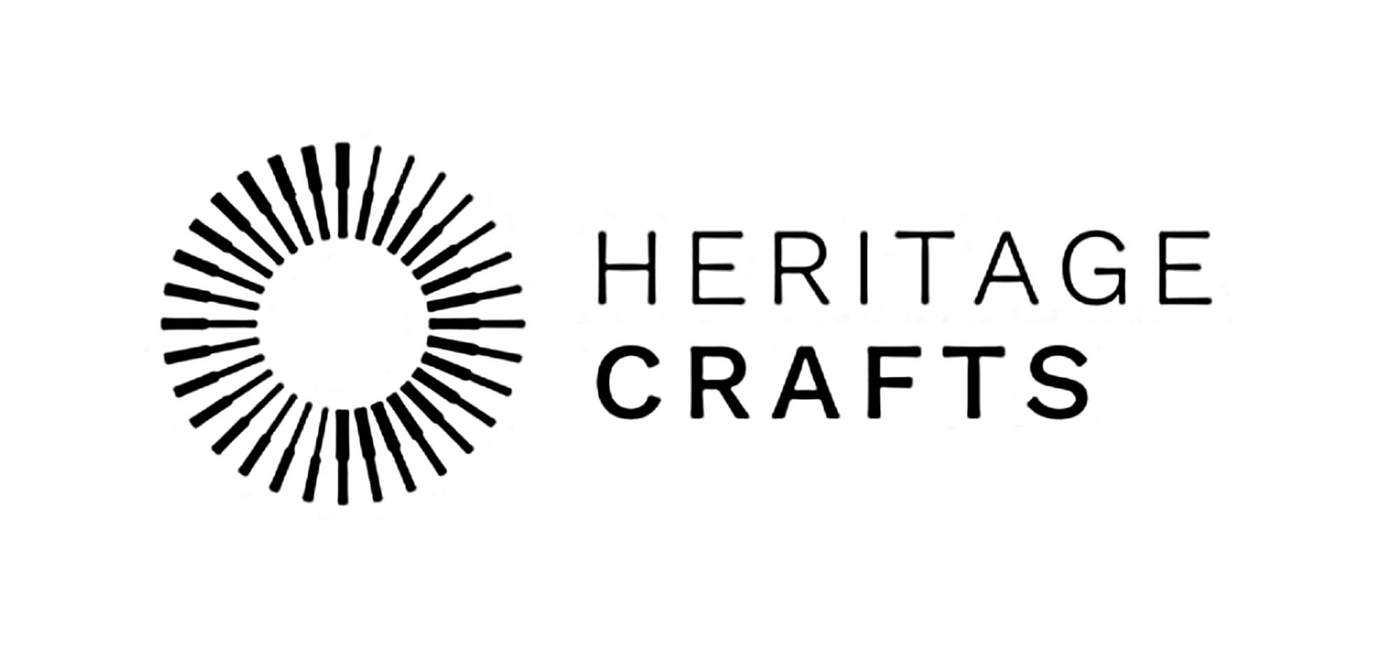 The Heritage Crafts logo. Heritage crafts is in black text on a white background. On the left side is a black wheel with black brushes and tools as black outline drawings in a circle.