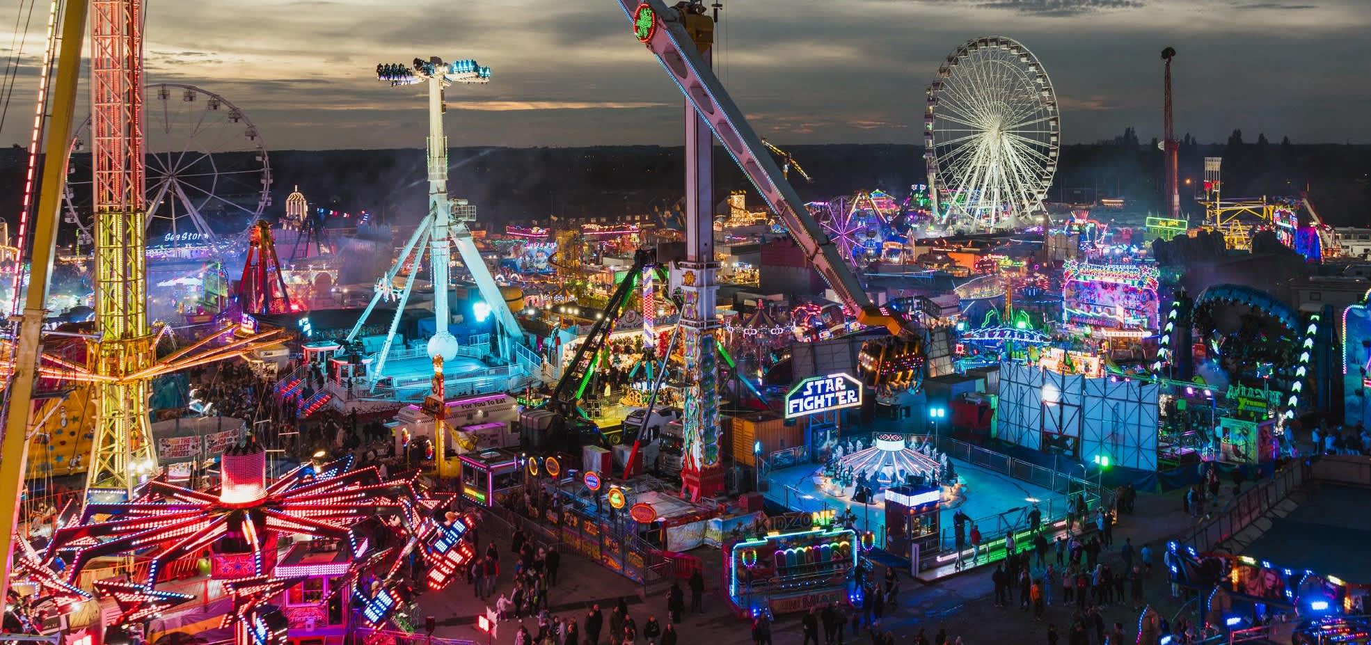 A panoramic view of Hull Fair at dusk with bright neon lights.