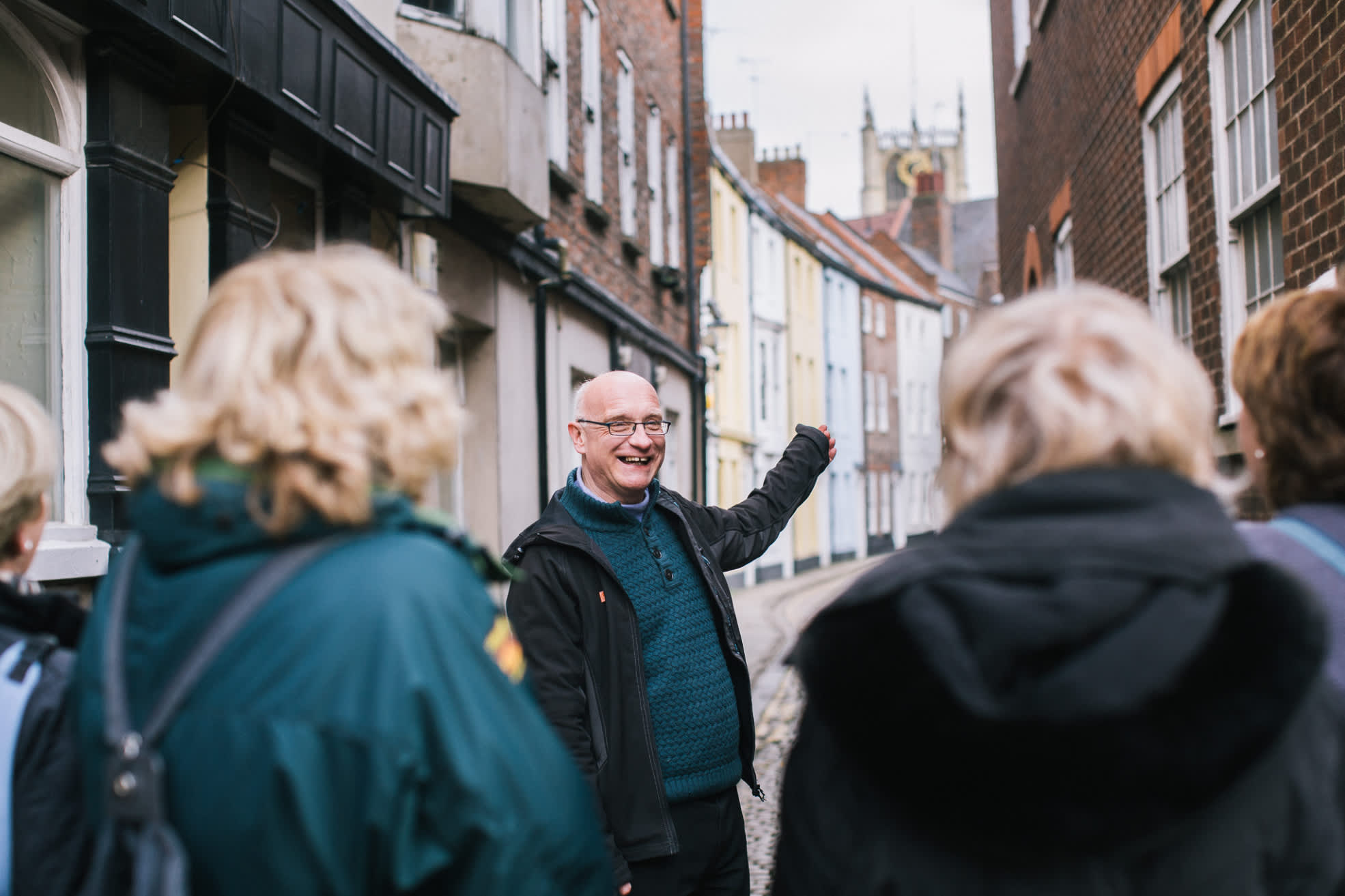 Group walking tour exploring Hull’s historic Old Town, with a guide pointing towards colourful period buildings along a narrow cobbled street.