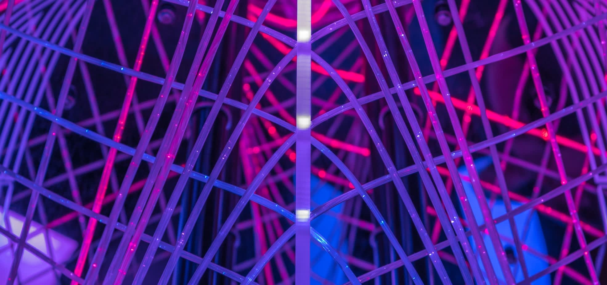 A bright art installation made of neon poles in pink and purple