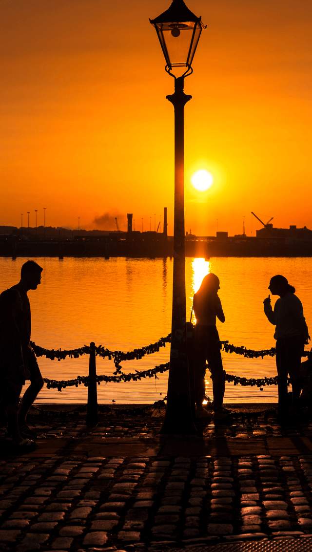 People watching the sun go down on the quayside of Liverpool Waterfront.