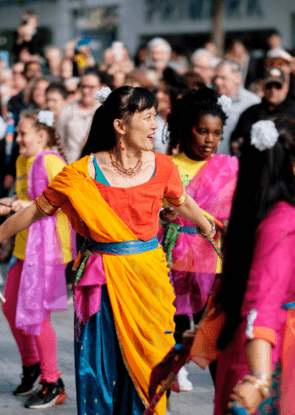 People in various colorful clothing dancing in the street