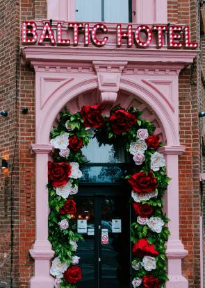 Exterior of Baltic Hotel with a pink doorway and flowers