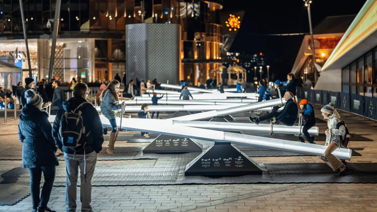 A line of see-saws lit up with people on them.