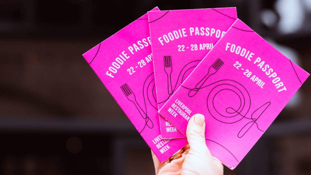A photo of someone holding pink booklets that have Foodie Passports written on them.