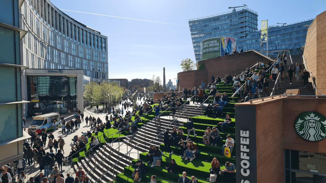 Liverpool one with large steps covered in fake grass with people sitting on them.