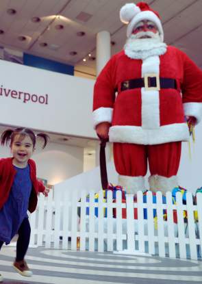 A young child stands next to giant santa figure in Museum of Liverpool