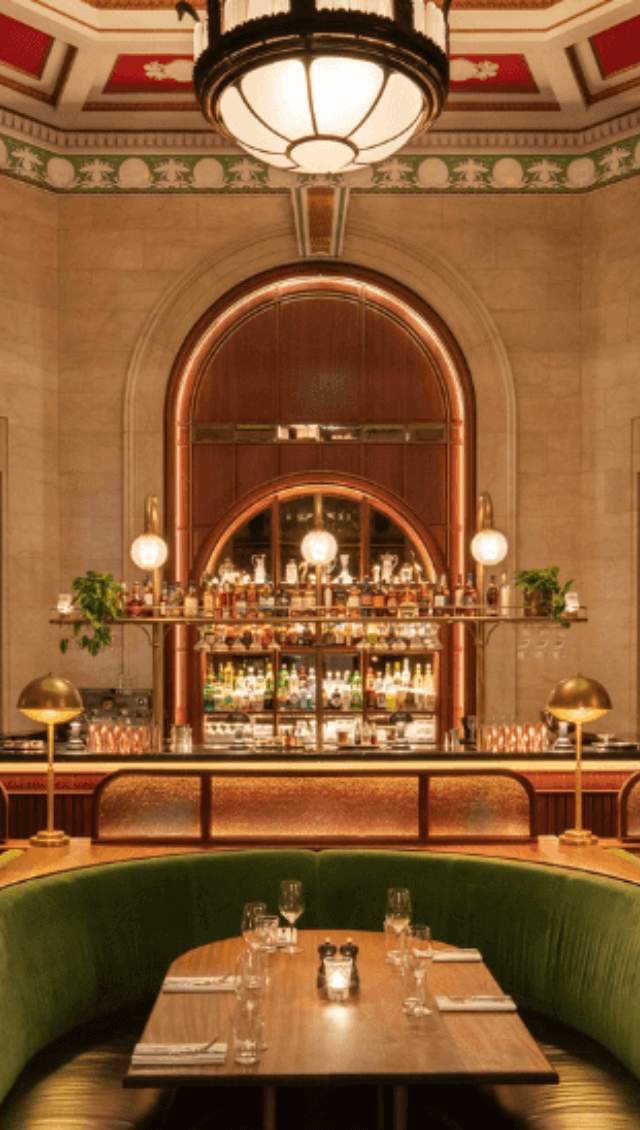 A portrait shot of an art deco interior bar with a large vaulted ceiling with red and green details.