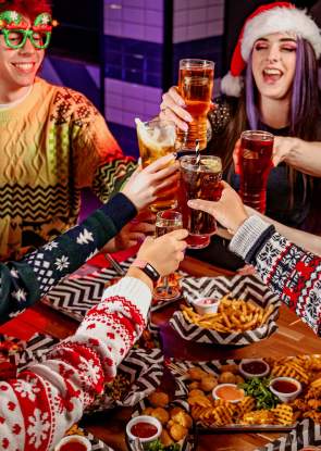 People in Christmas jumpers drinking cocktails with fun glasses on