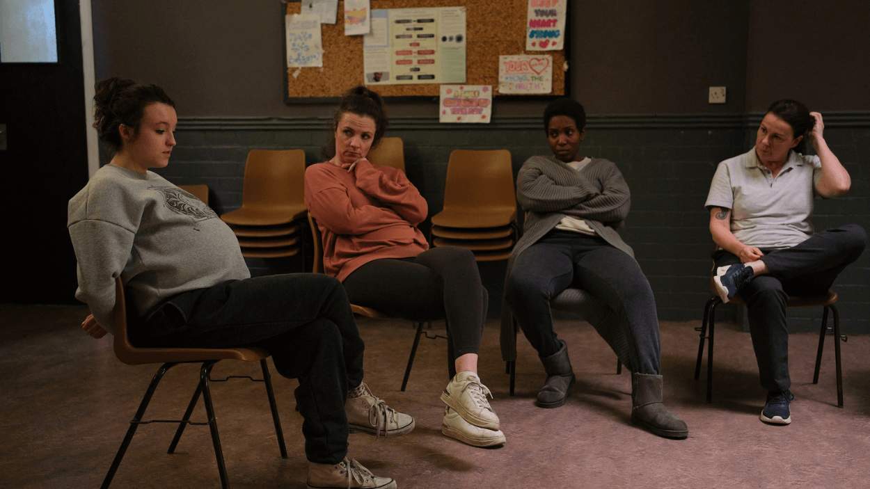 Four people sitting on chairs in a room as part of a film set.