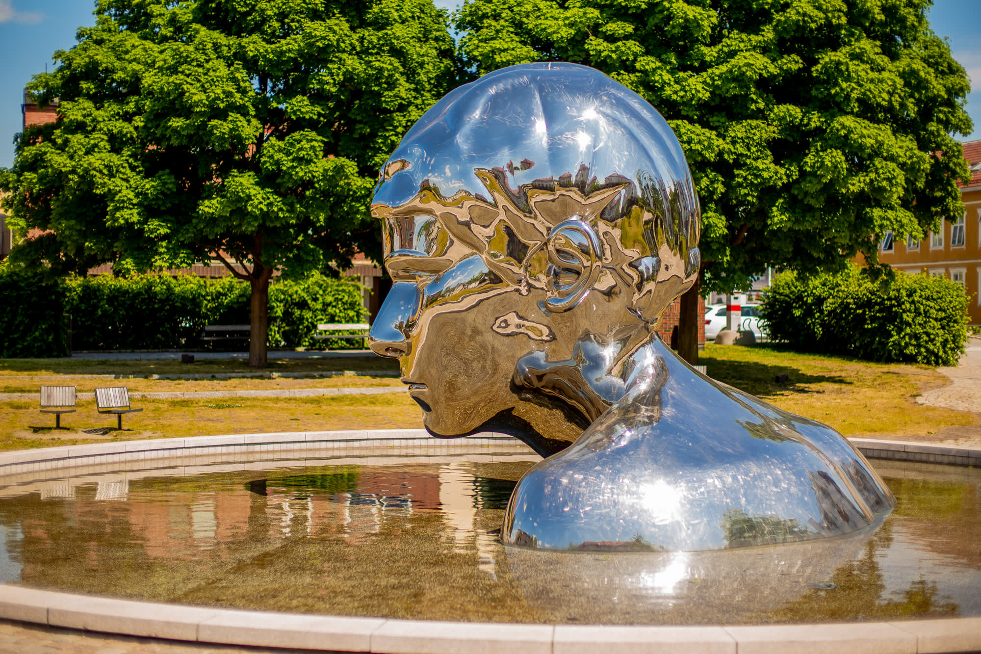 Skulpturen Genesis i krom og vannspeilet rundt, i Sarpsborg. Foto.