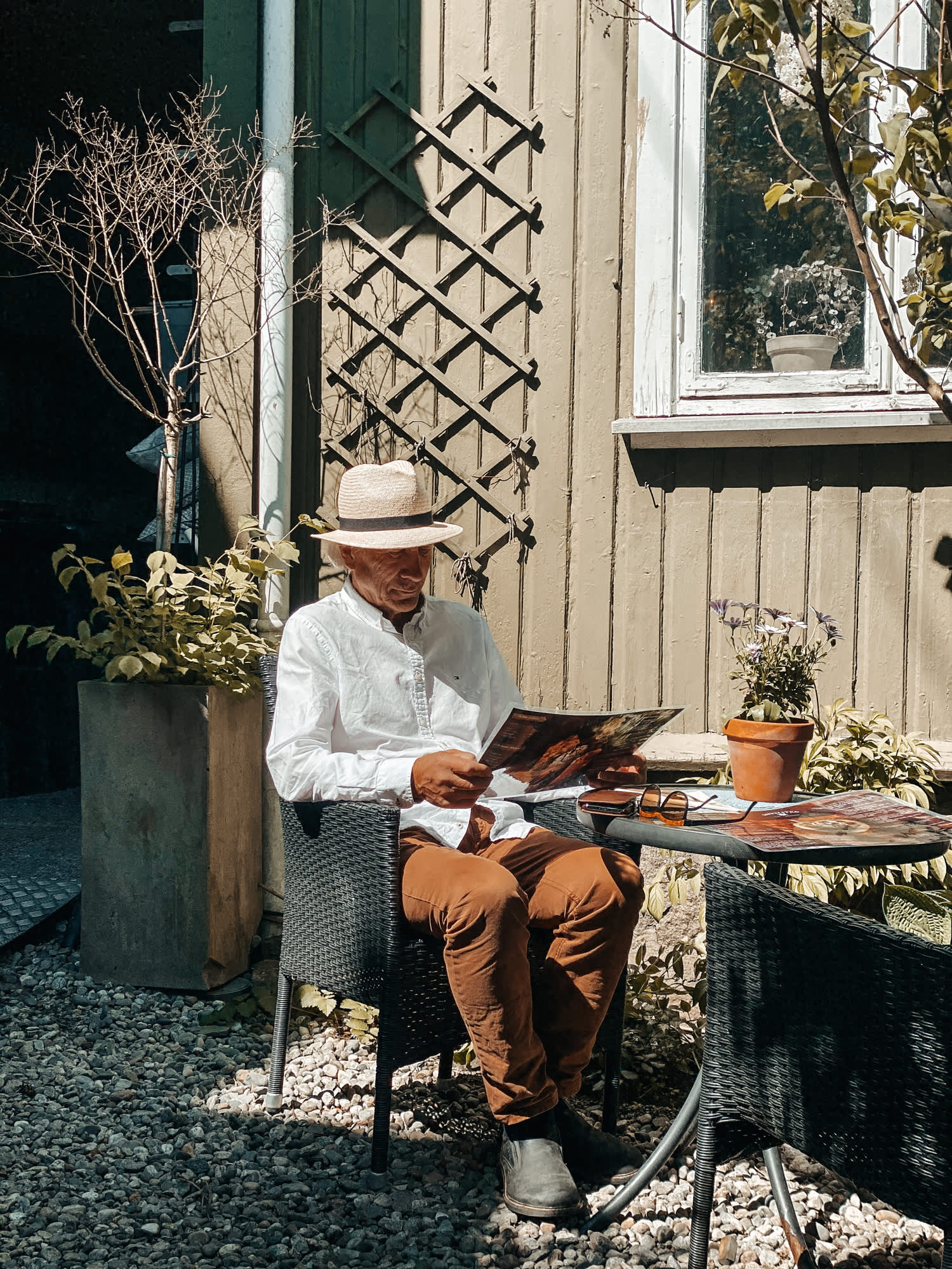 Mann med hatt som sitter og leser avisen på et kafébord i Sarpsborg. Foto.