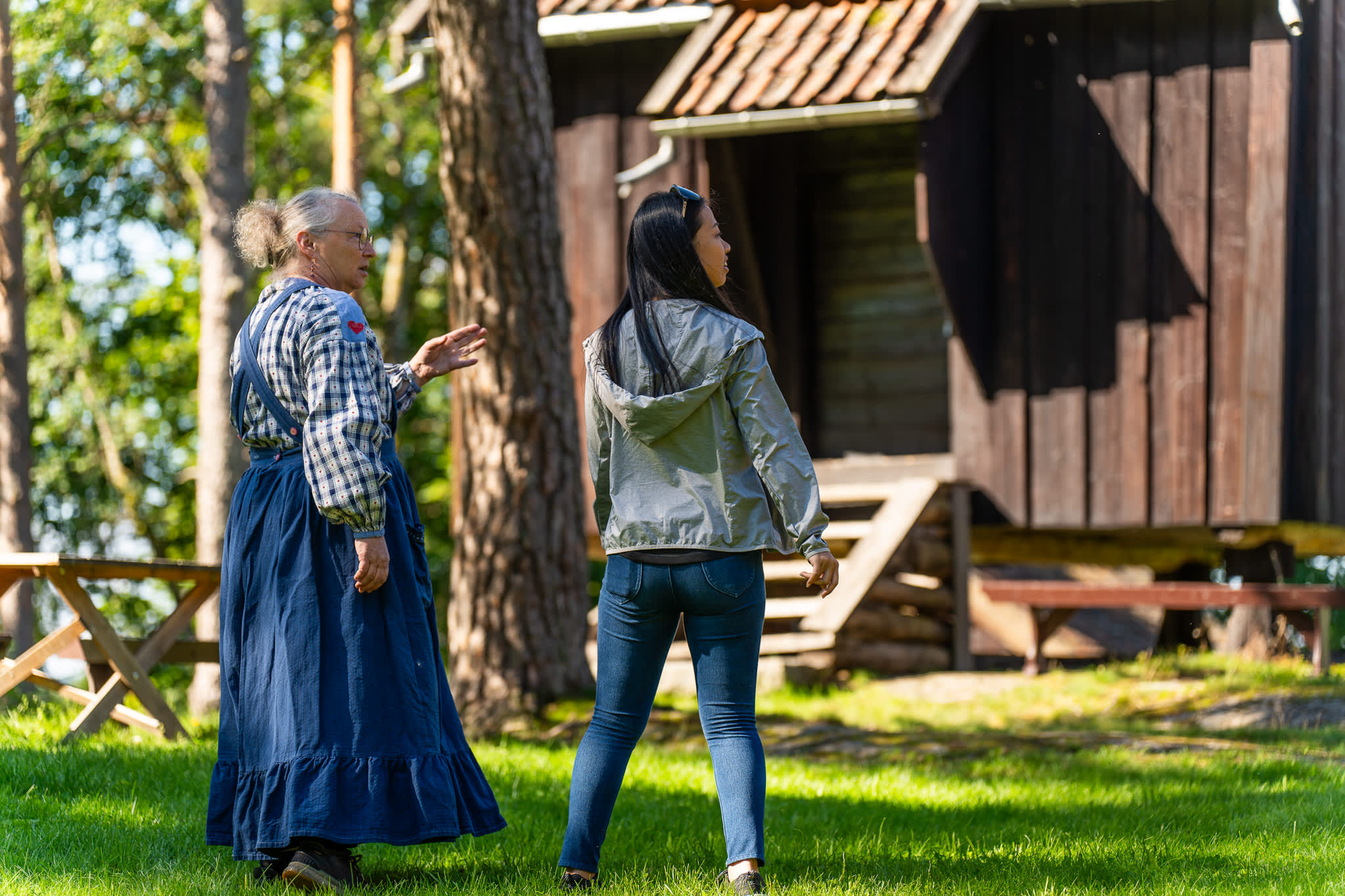 Omviser og to publikumer i snakk foran en av de historiske bygningene på Trøgstad bygdemuseum