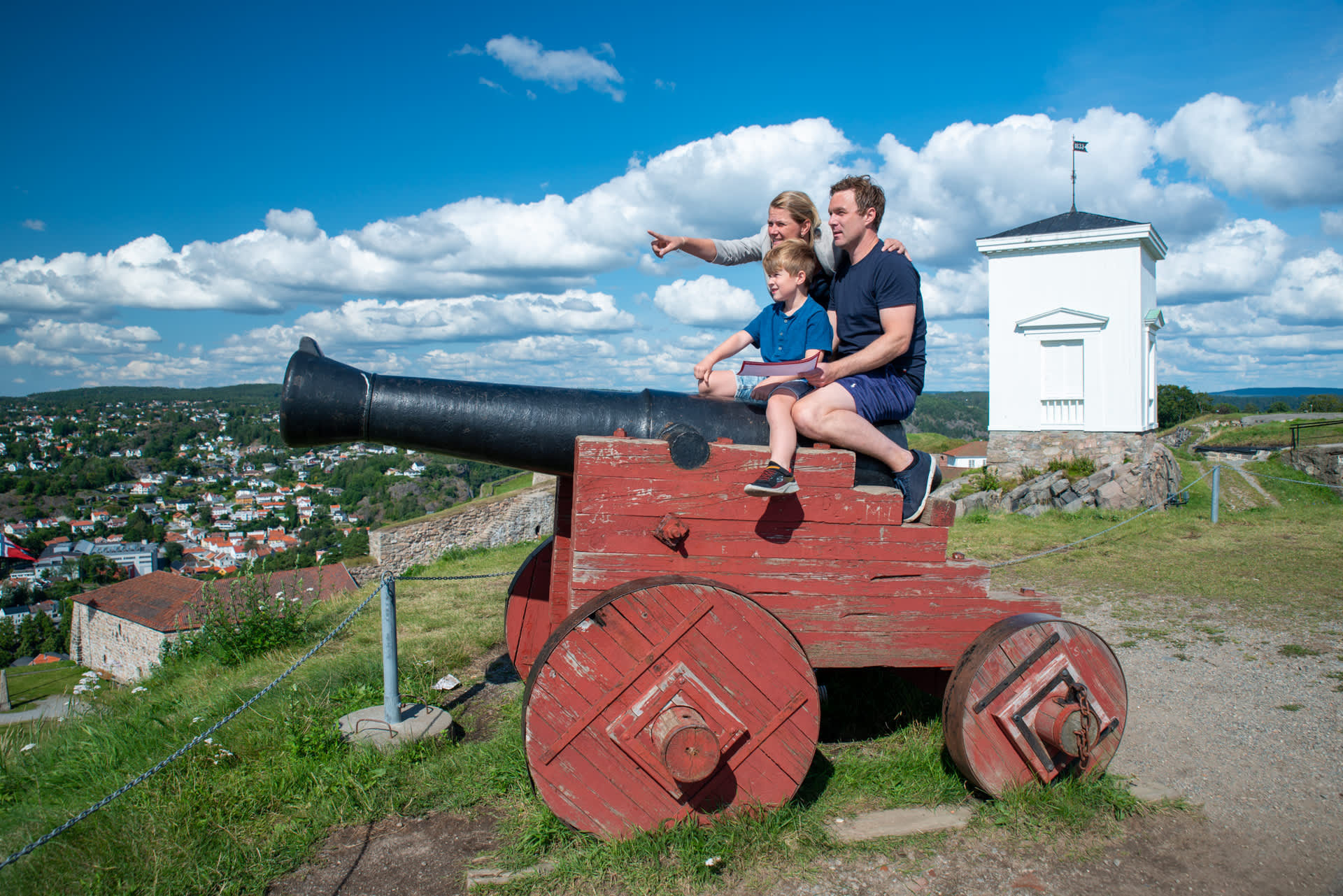 Familie som sitter på en kanon på Fredriksten festning i Halden.