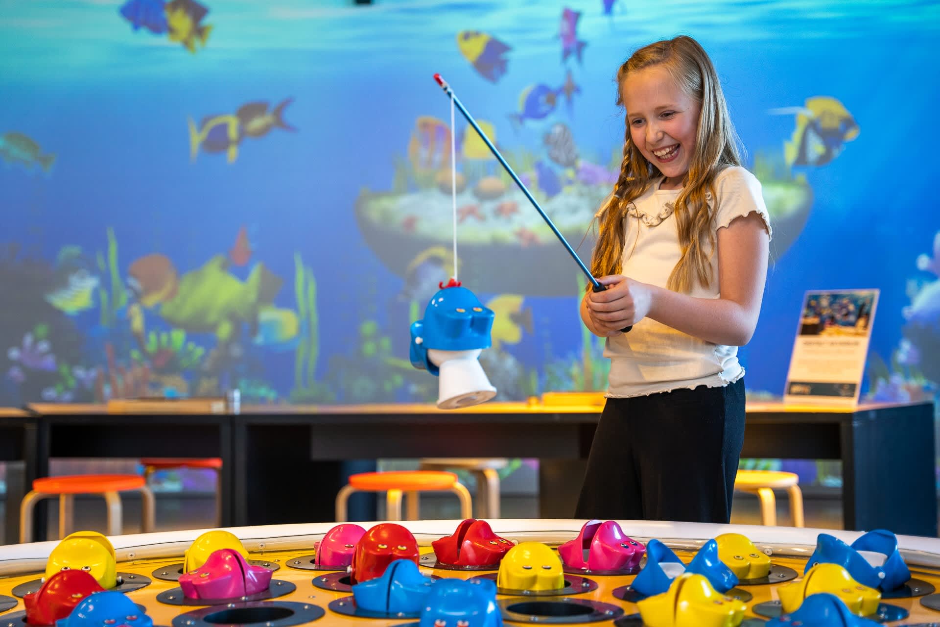 Smilende jente som tester det store fiskespillet på INSPIRIA science center