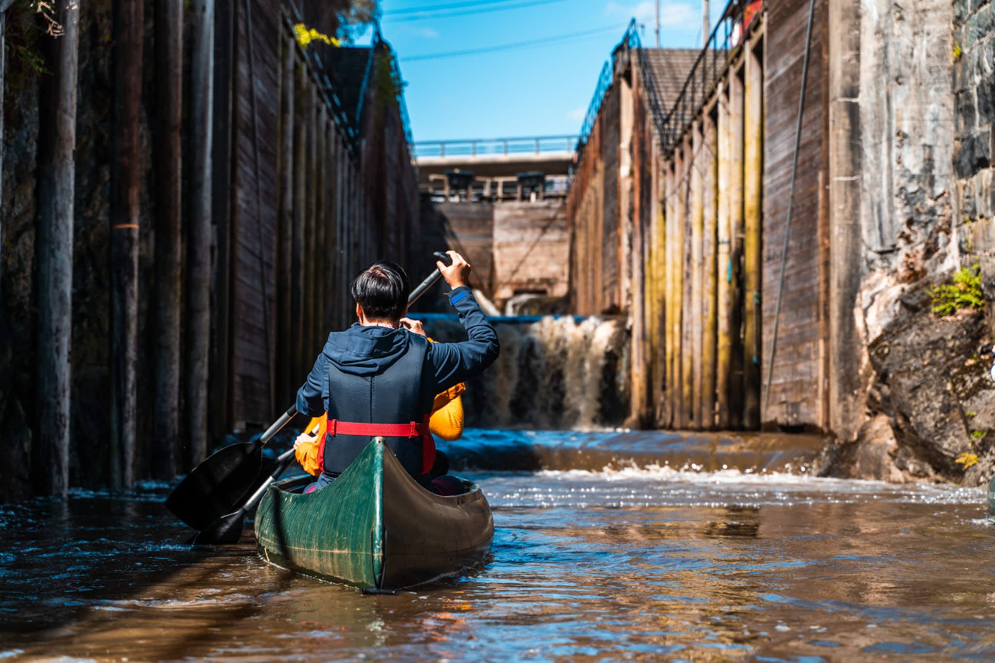 Man in canoe paddling into lock chamber.