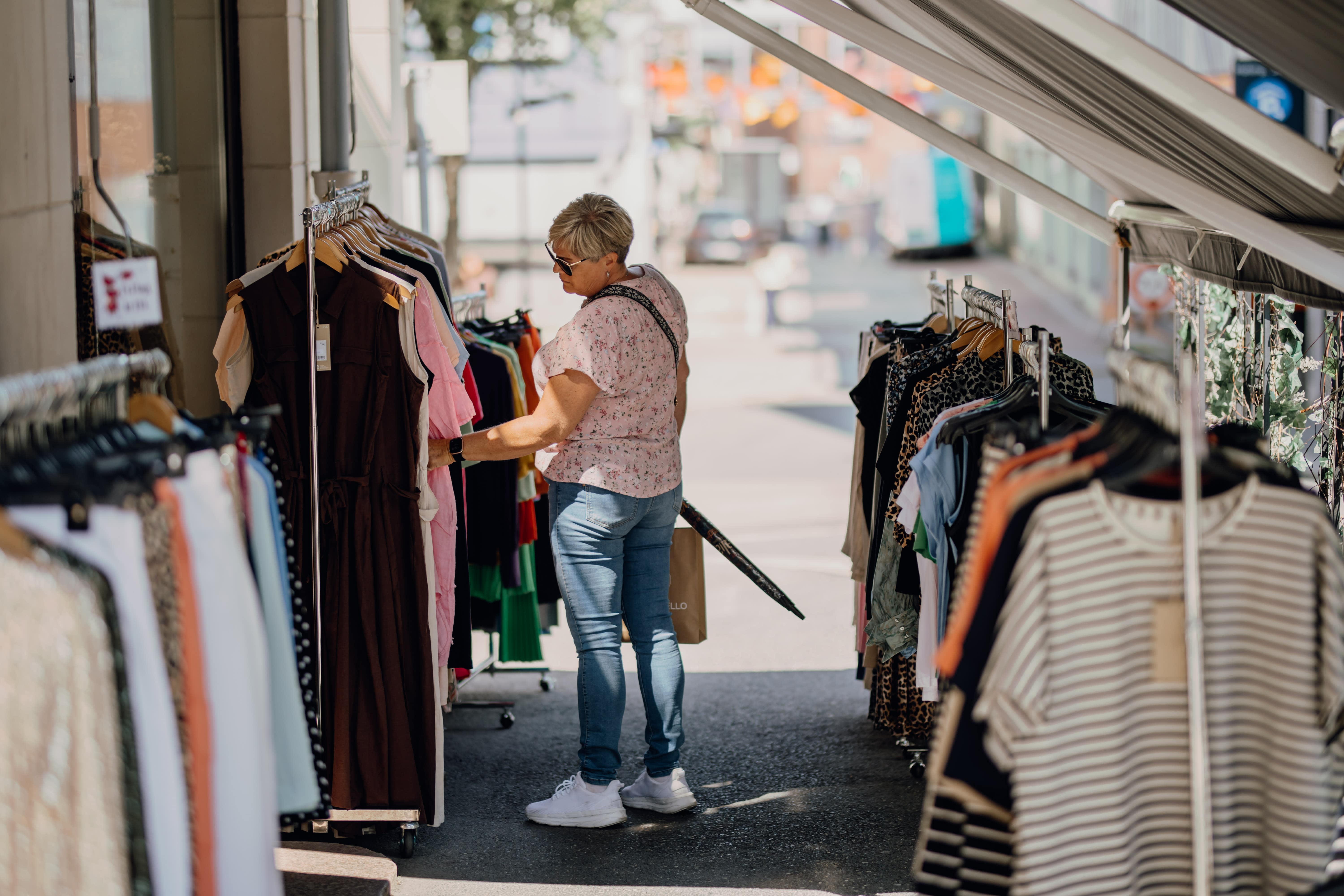 En dame som ser på klær utenfor en butikk